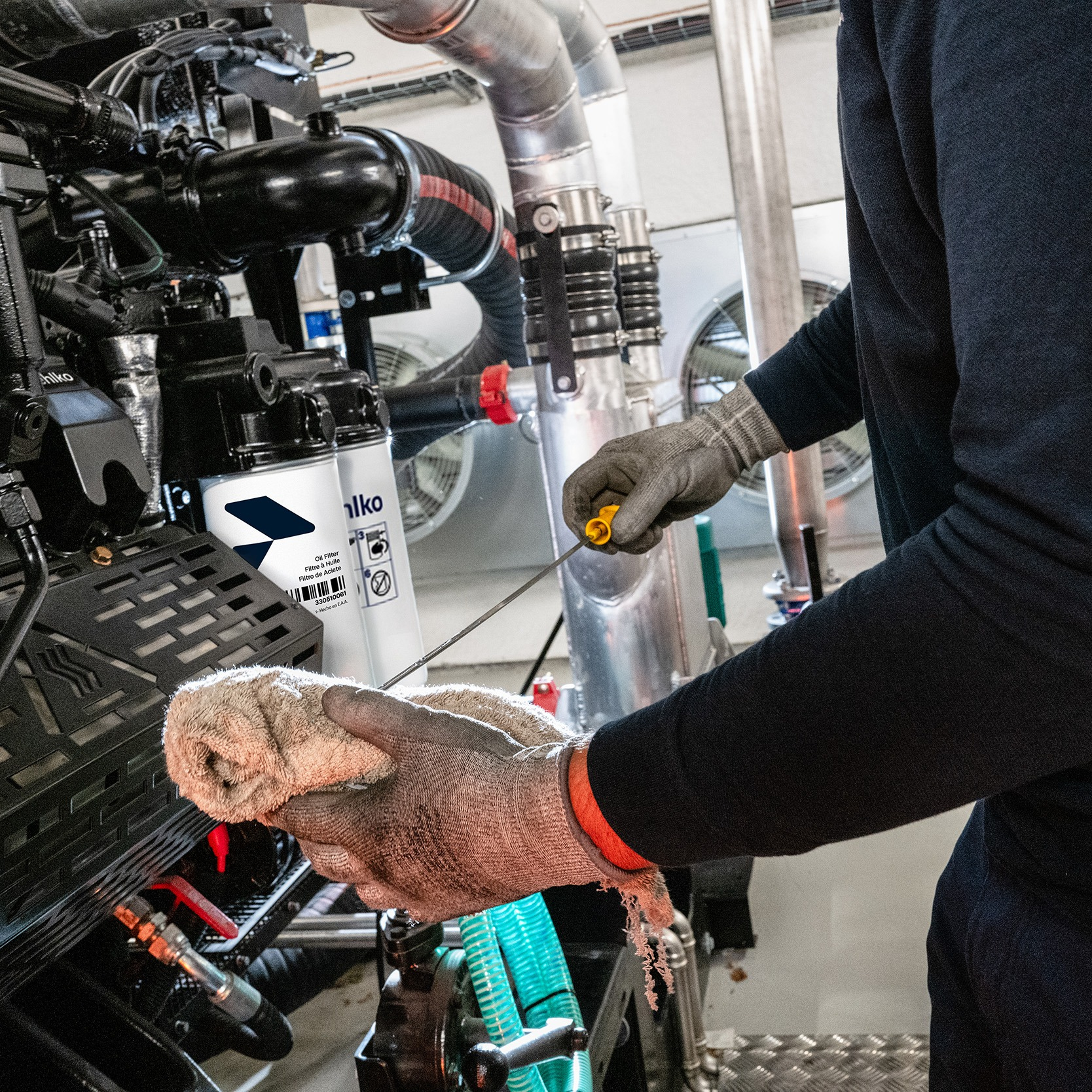A man with dipstick and a rag checking the oil level of a generator